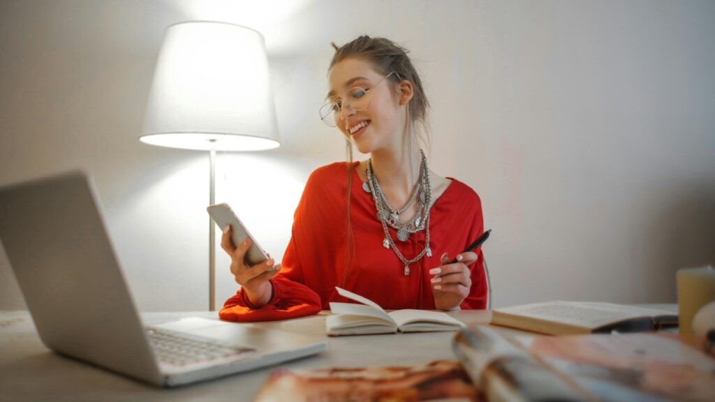 Mulher olhando celular e fazendo anotações