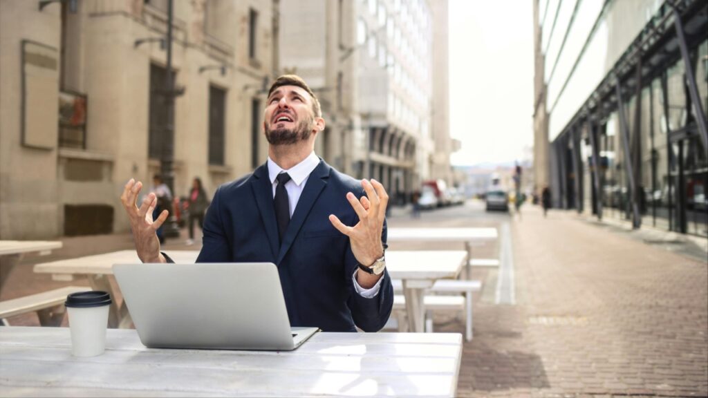 Homem de terno frustrado e notebook sobre a mesa