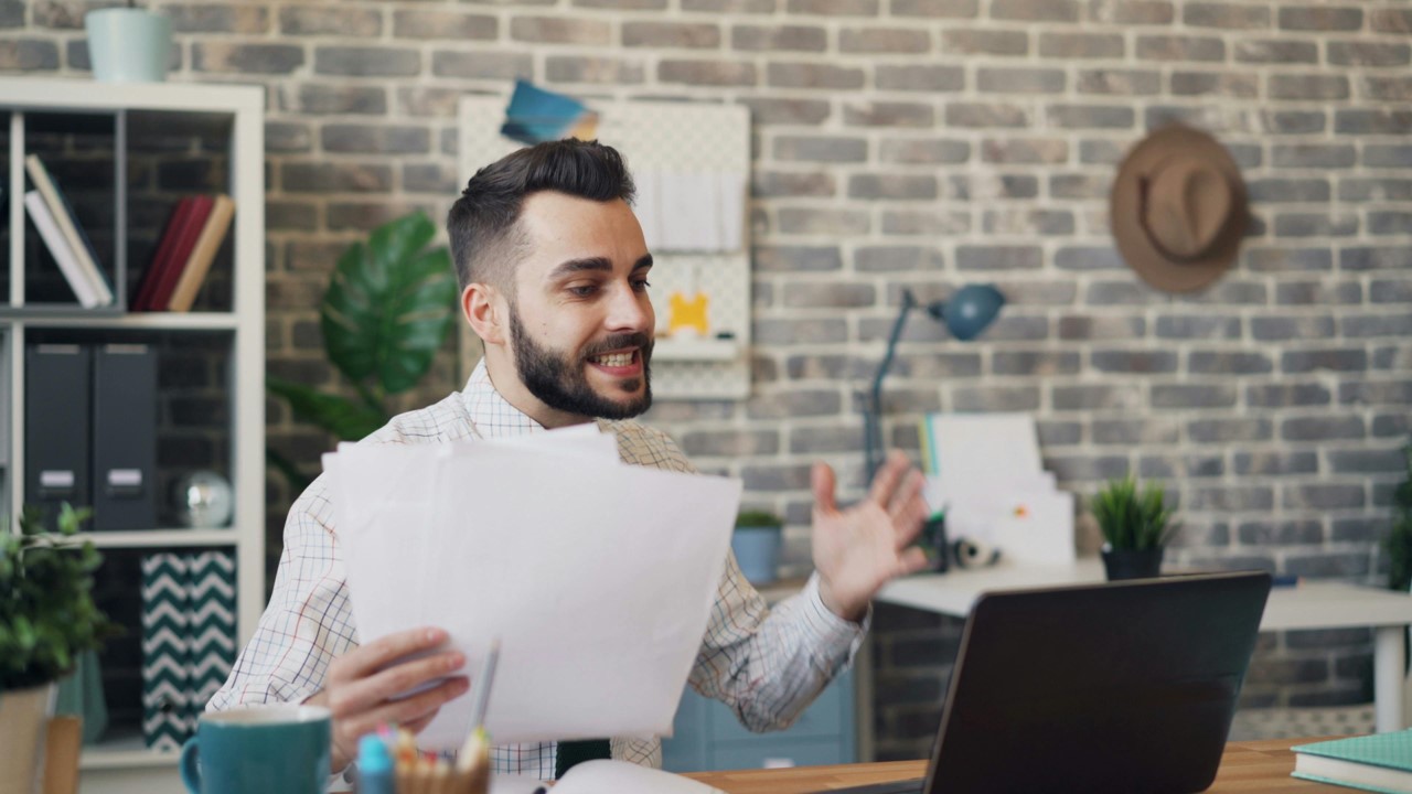 Homem fazendo reunião com notebook e segurando papéis